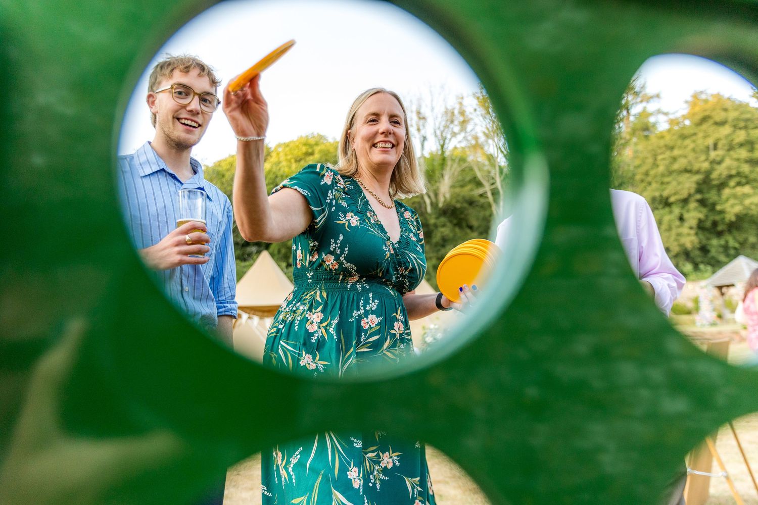Creative photo framed through foliage showing guests enjoying an outdoor celebration.
