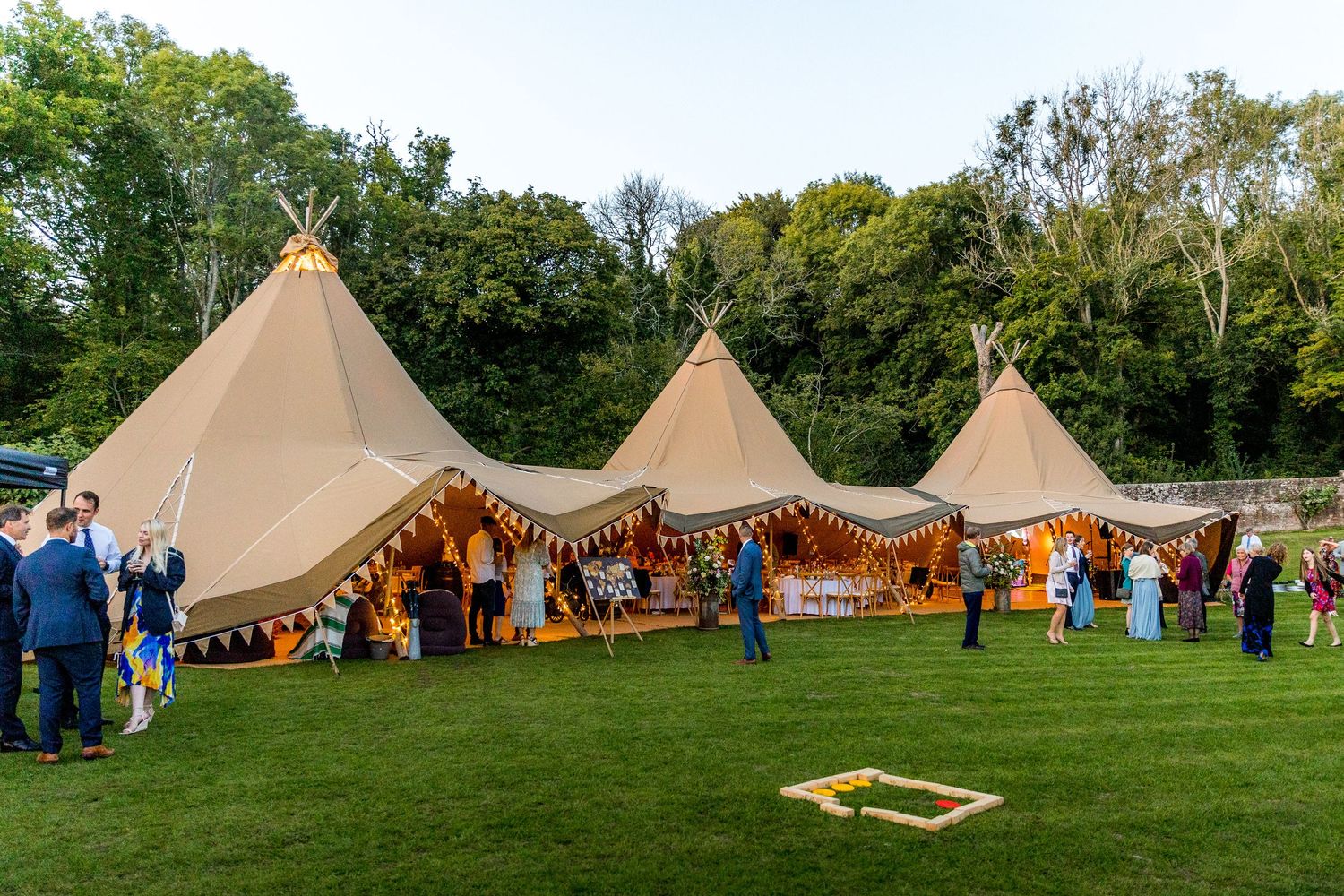 Multiple connected tipi tents create a unique outdoor wedding venue space.