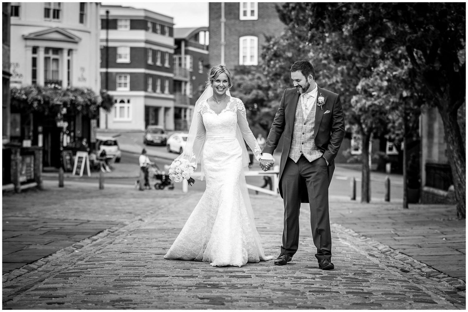 A black and white wedding photo series showing a couple walking together on a cobblestone street.