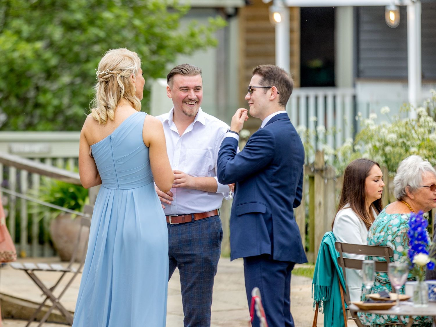 Wedding party and guests mingling on an outdoor patio during a summer celebration.