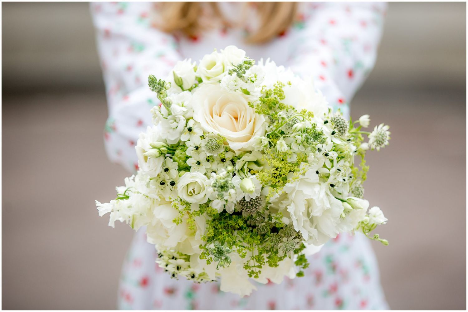 Delicate white and green floral wedding bouquet with roses and baby's breath.