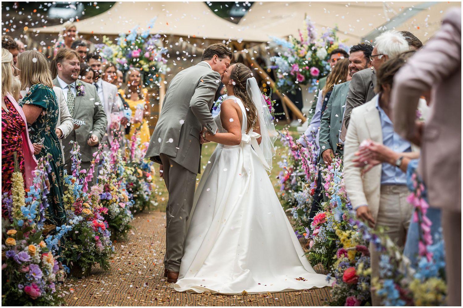The couple pause for a kiss as they walk down the aisle together after their marriage.