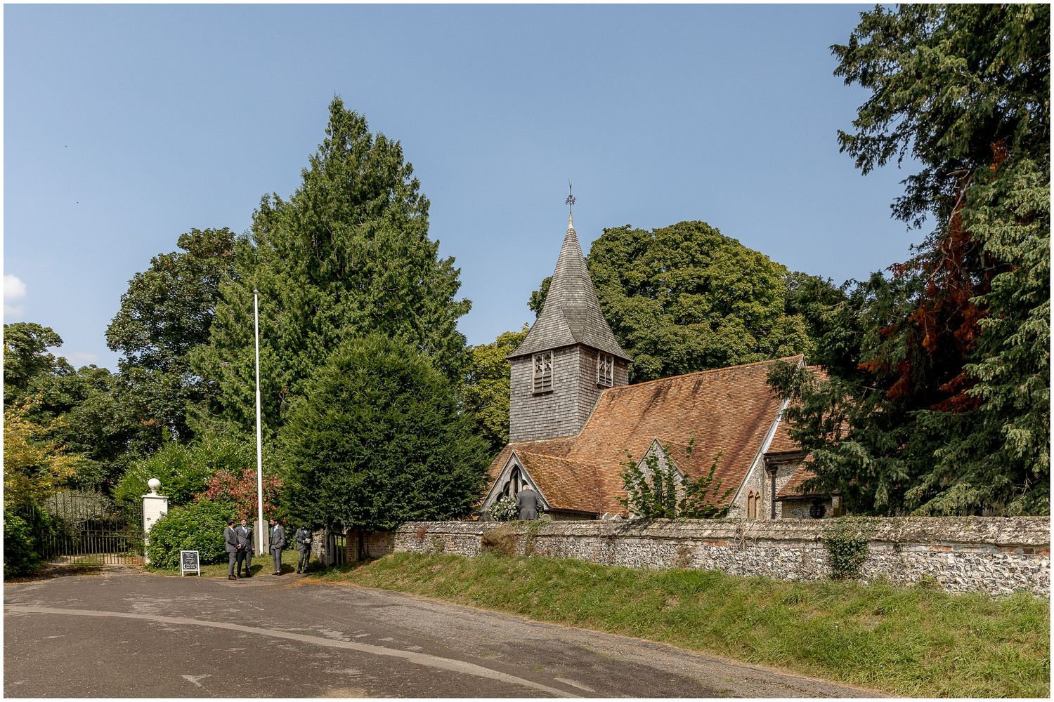 Panoramic view of traditional English countryside church with red tile roof and stone walls.