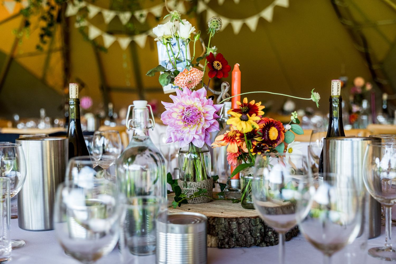 Elegant table settings with floral centerpieces and bunting decorations at a rustic wedding reception.