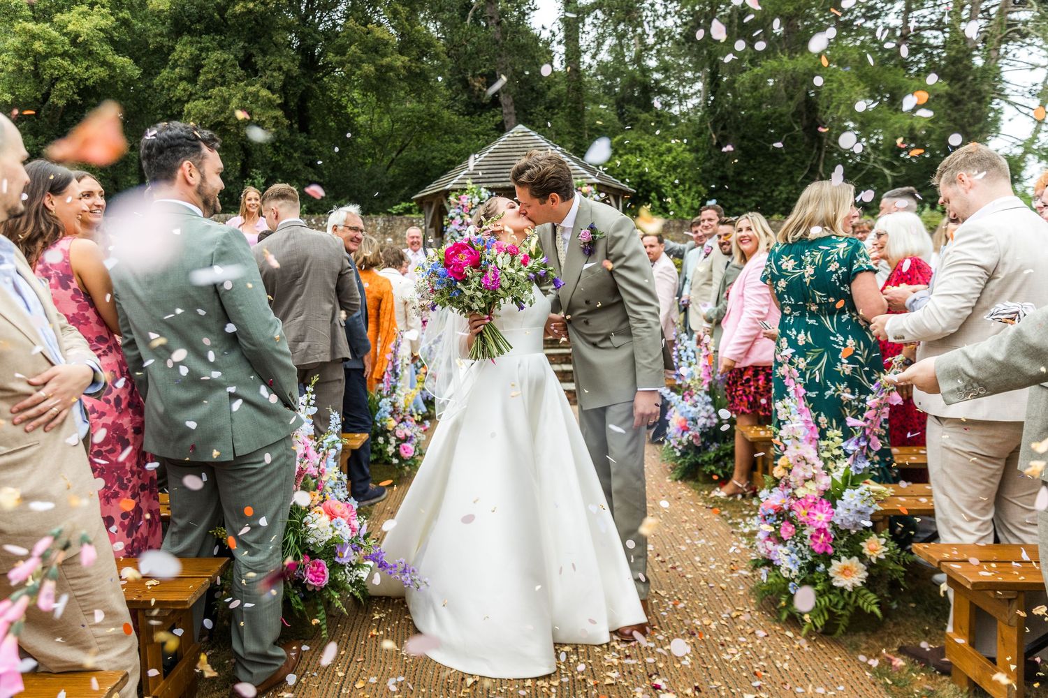 Outdoor wedding reception with rustic wooden benches and floral decorations.