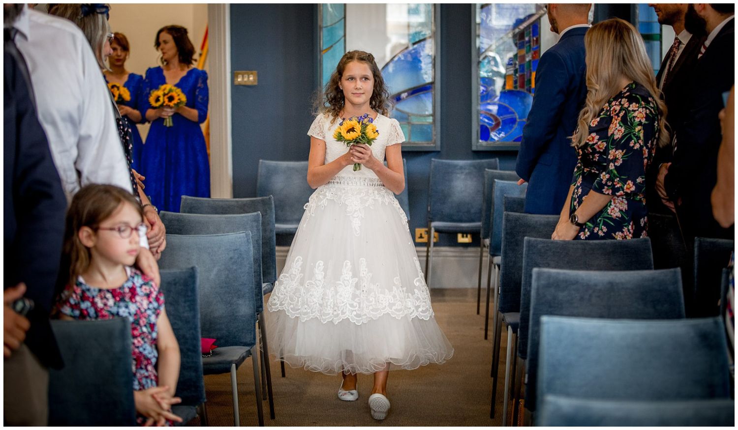 Wedding guests mingle and socialize during a reception in an elegant indoor venue with dark walls.