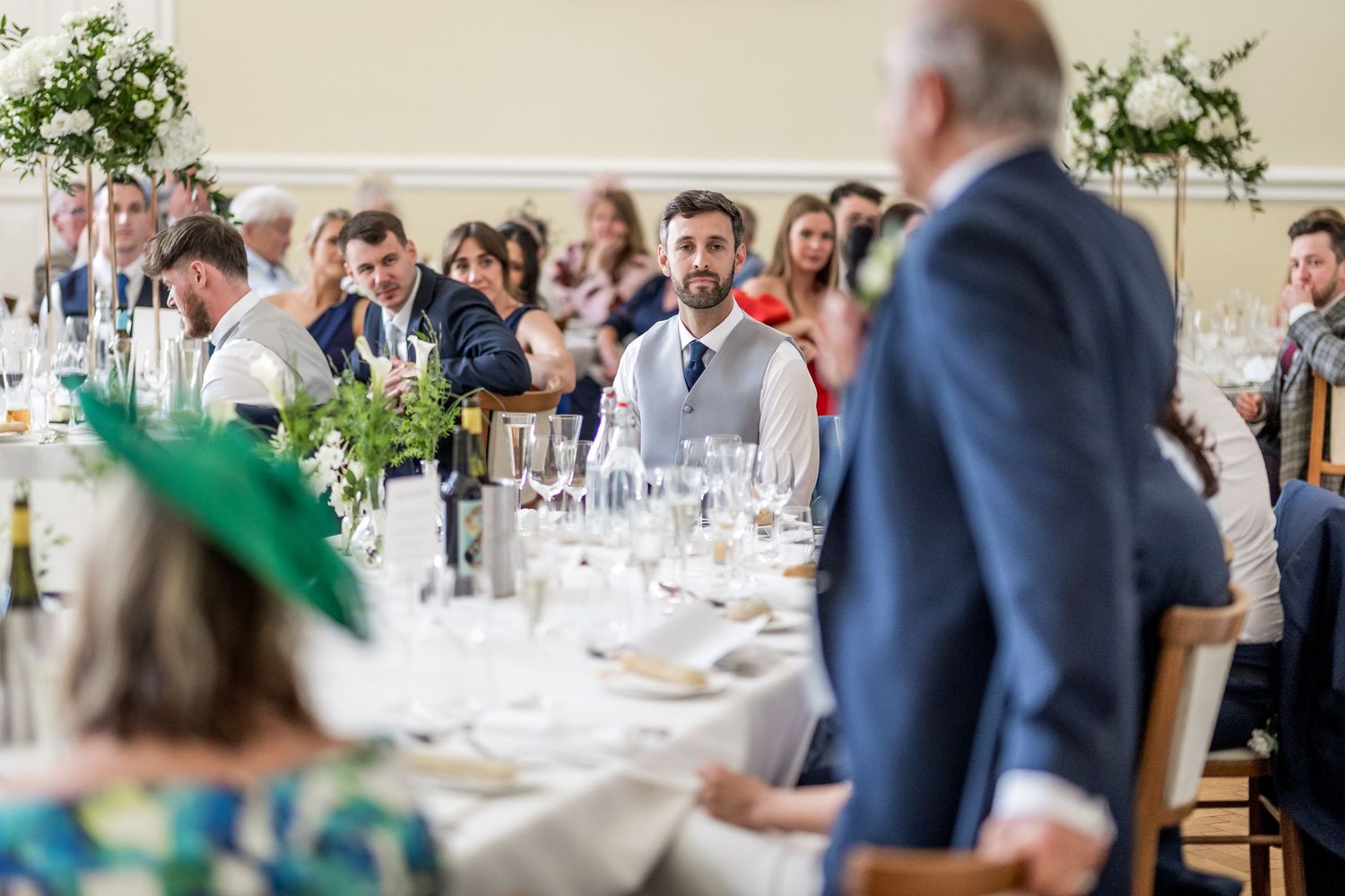 Elegant wedding reception venue with white table settings and natural light streaming through windows.