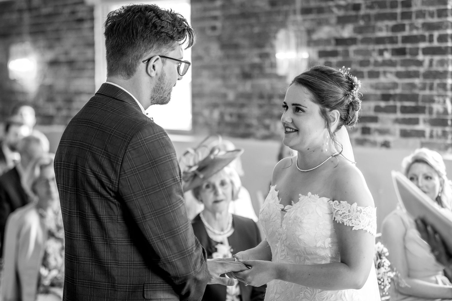 Black and white photo of wedding ceremony in industrial venue with brick walls.