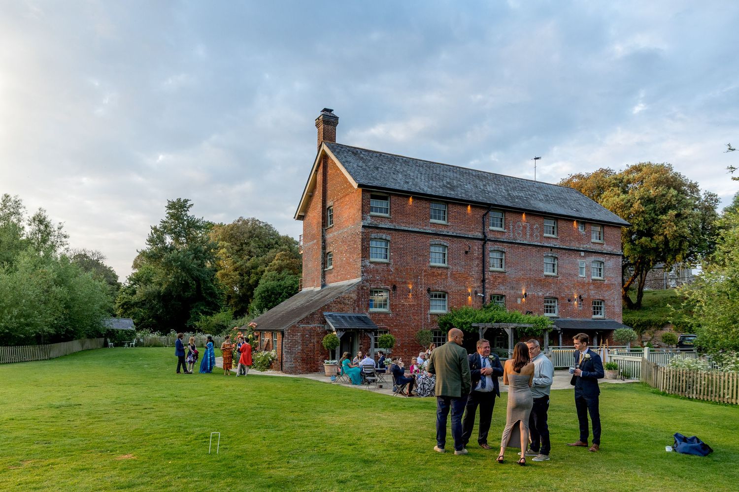 Wide shots of a red brick wedding venue with guests gathered outside on the grounds.