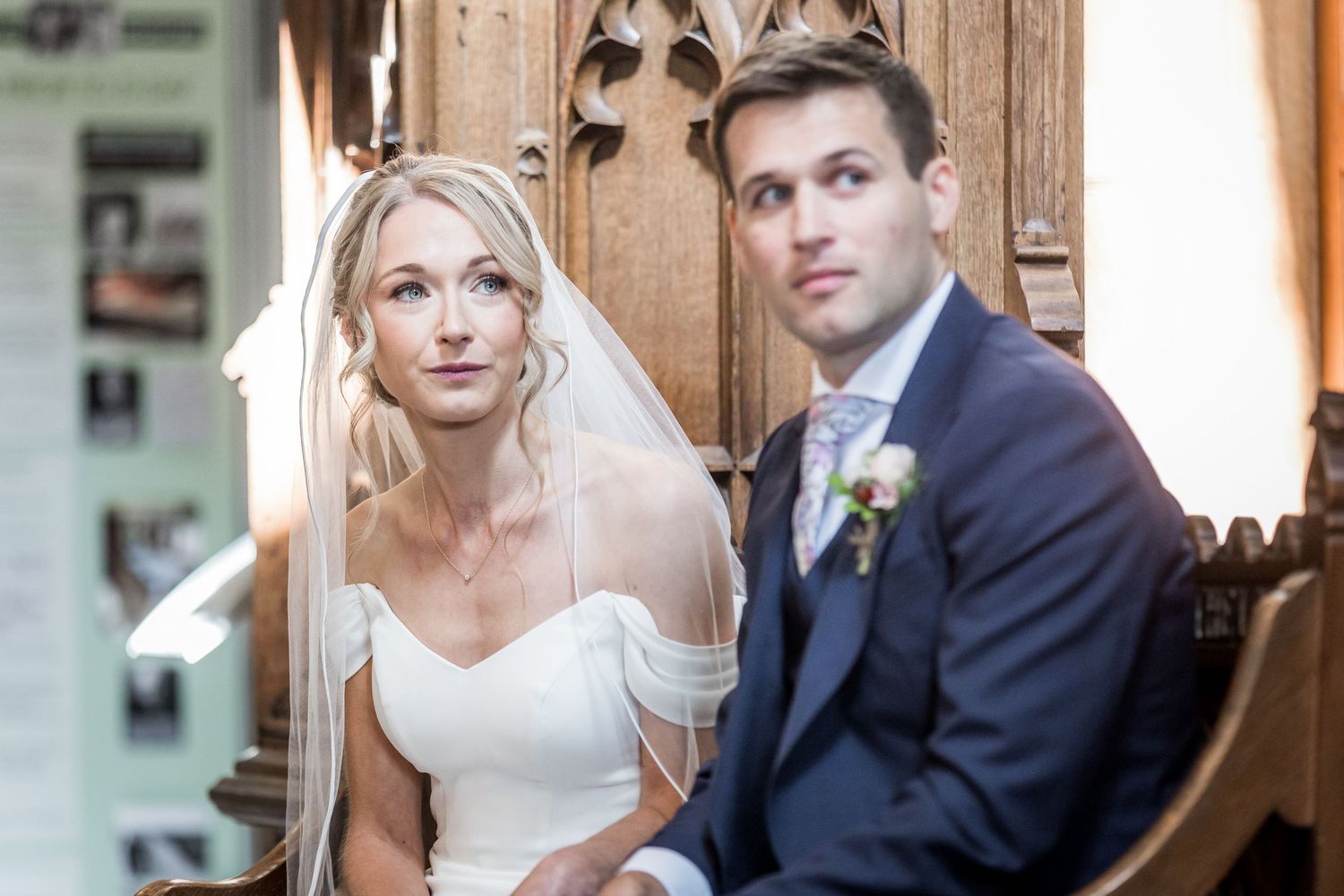 Couple poses for wedding portraits in rustic setting with sunlit windows.