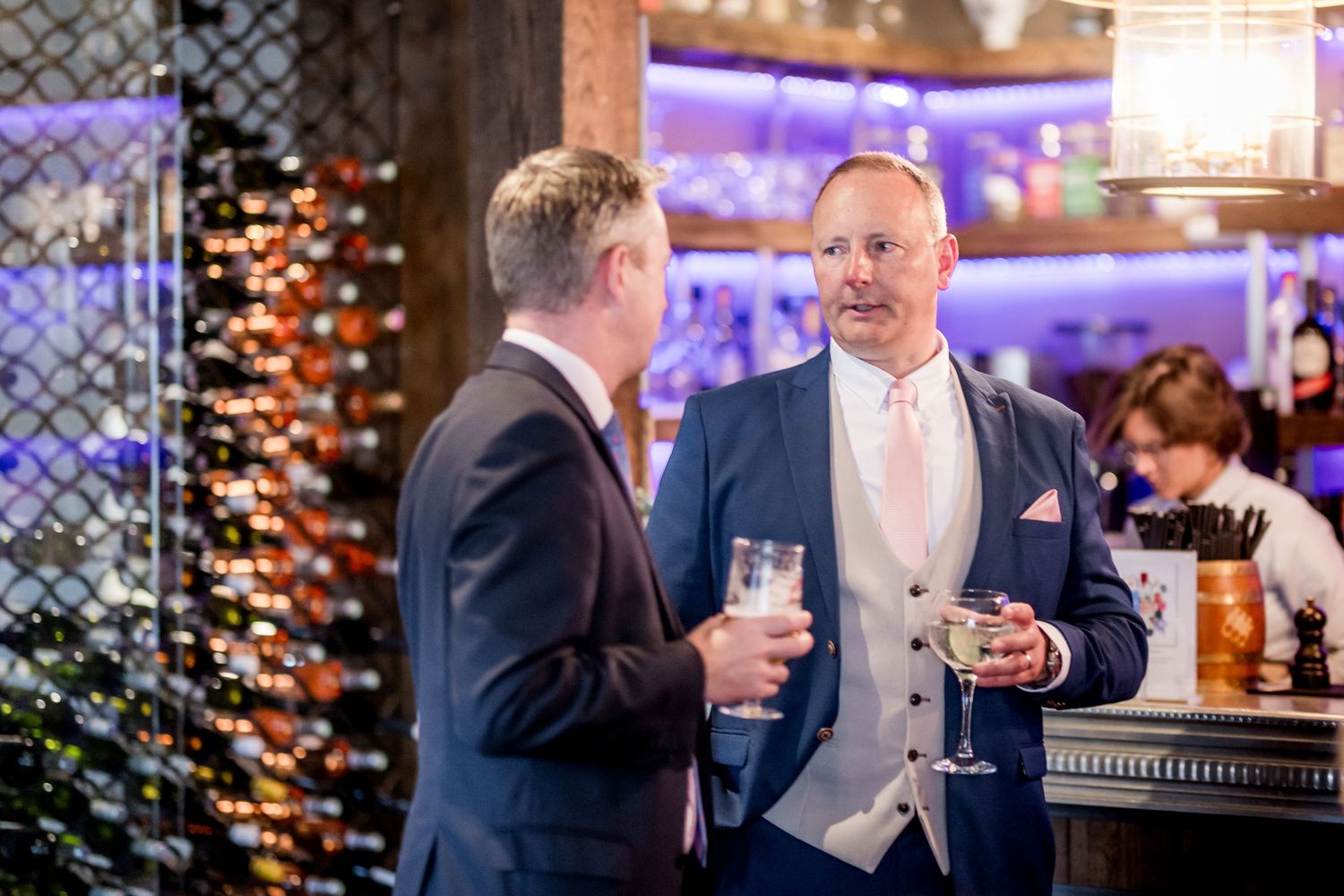 Elegant evening reception with guests mingling near a well-lit bar area.