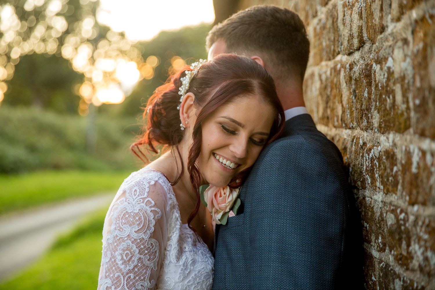 Bride and groom pose for a couple wedding photograph by the stone barn just outside Southdowns Manor wedding venue near Petersfield