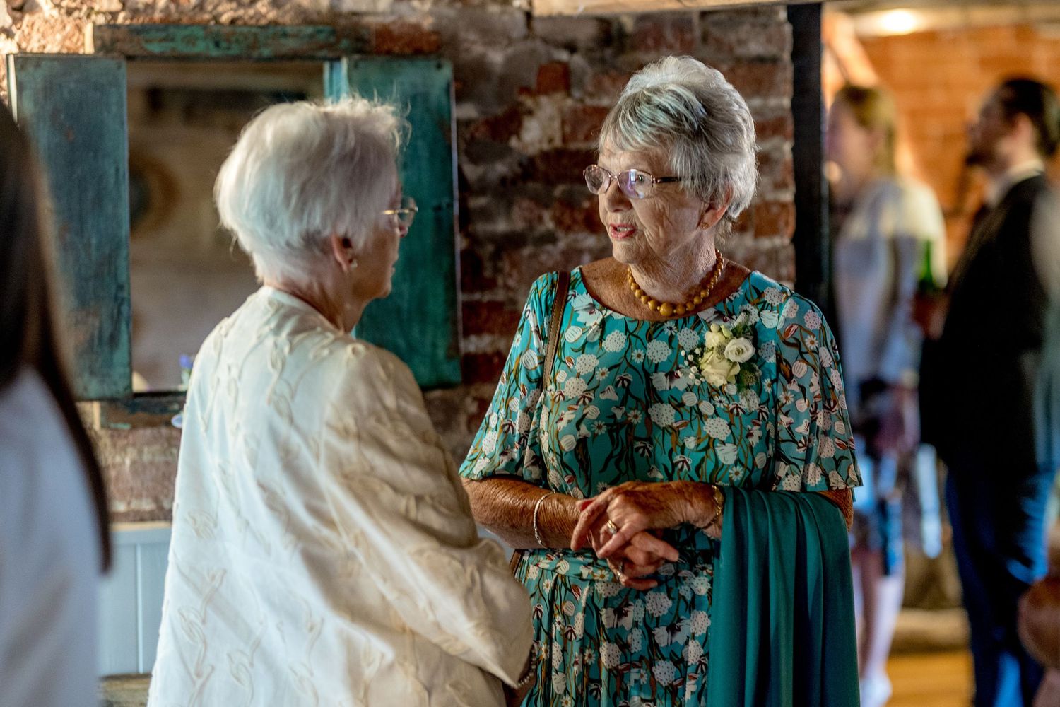 Guests in formal attire interact during celebration in historic venue.