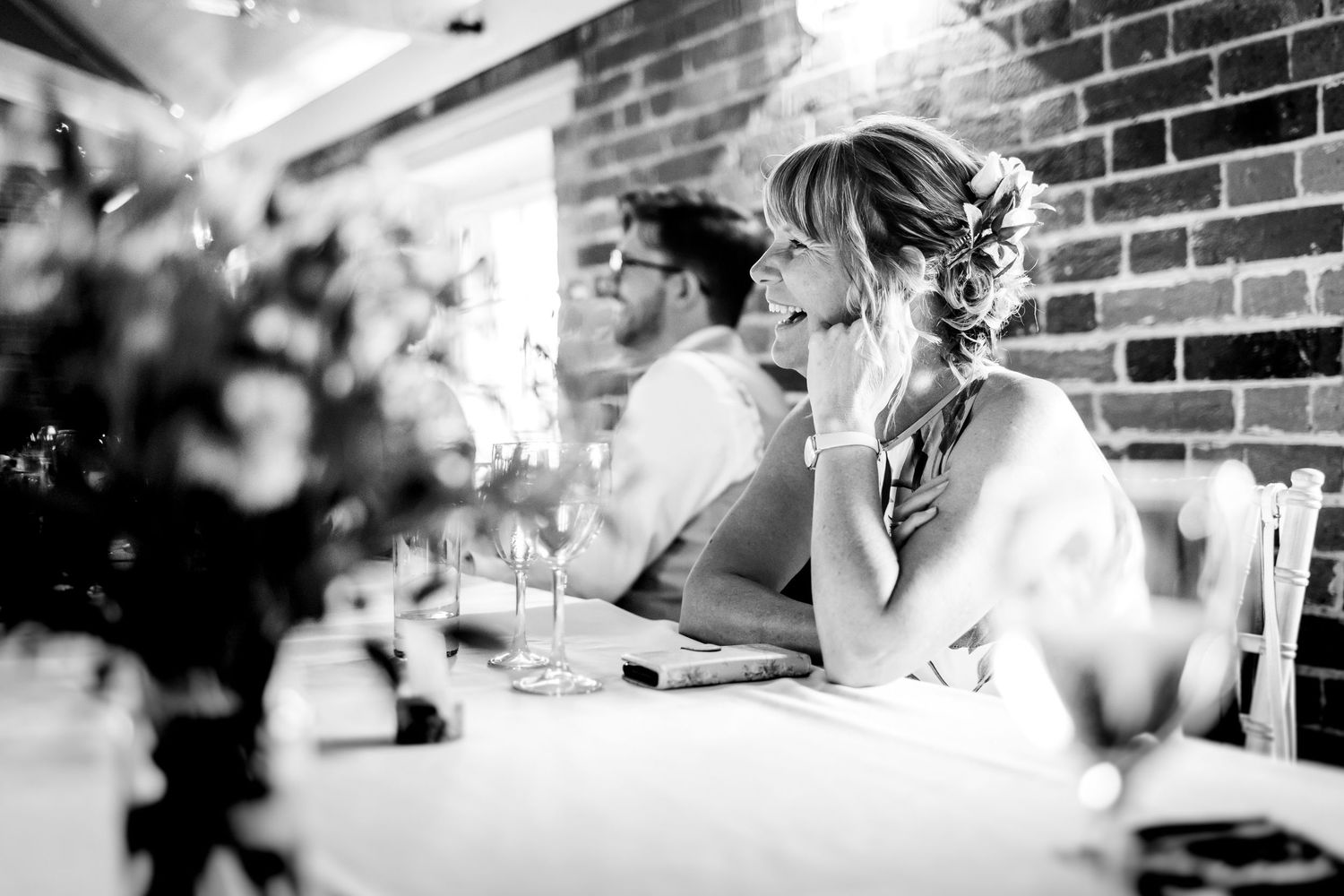 Candid moments captured during wedding reception dinner in industrial-style venue.