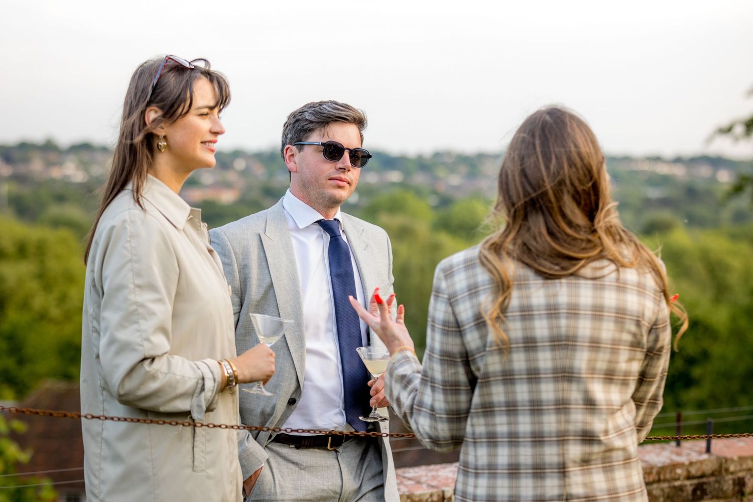 Wedding guests enjoying outdoor cocktail hour with countryside views.