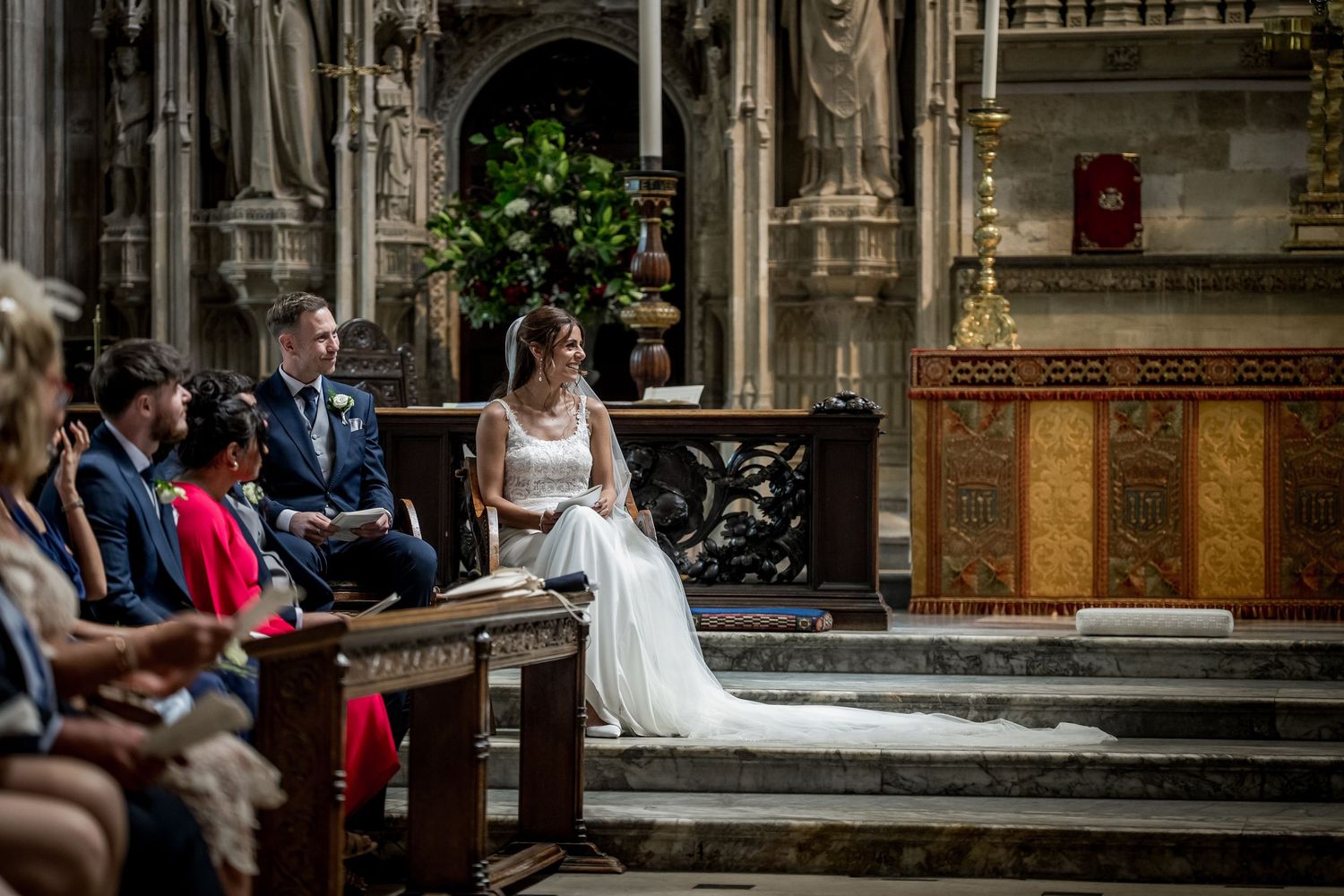 Elegant church wedding ceremony with guests seated in wooden pews beneath Gothic architecture.