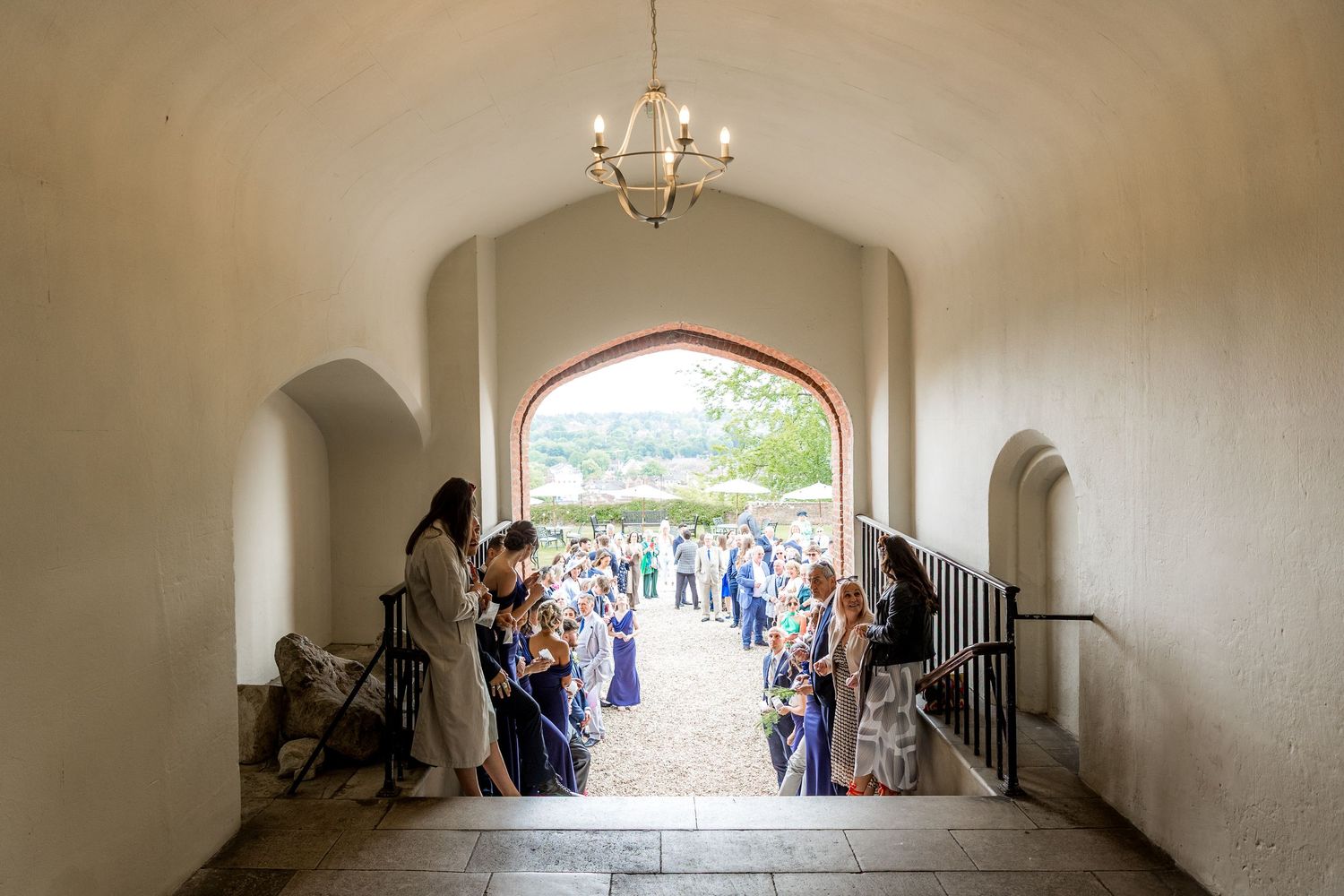Panoramic view of a wedding ceremony venue with arched windows and chandelier.