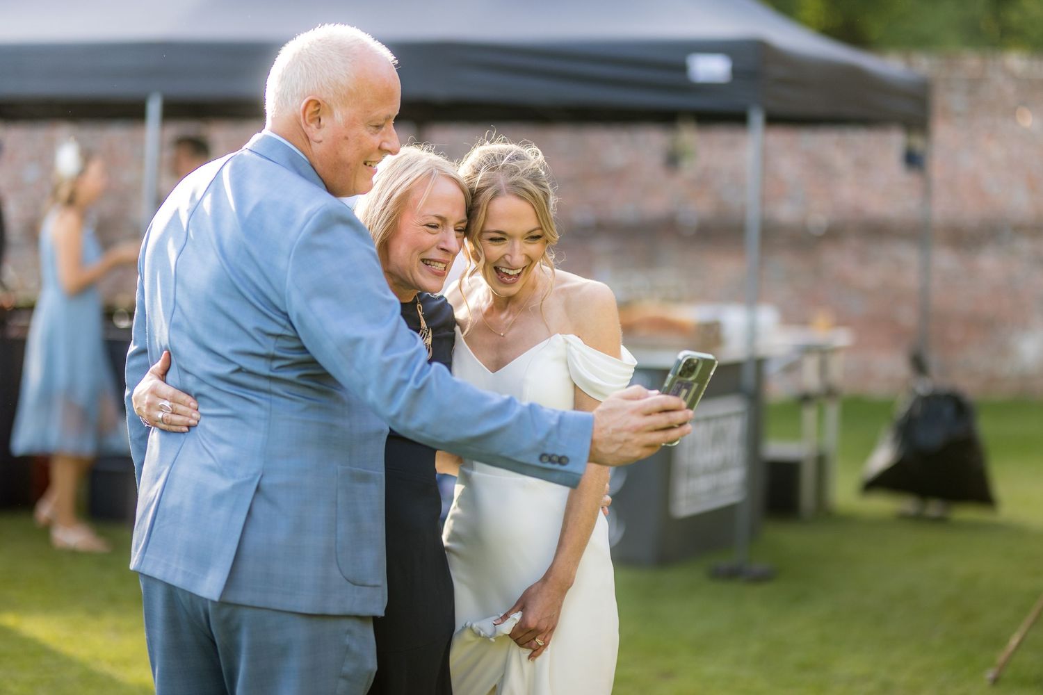 Emotional moment shared between guests looking at something together during an outdoor celebration.