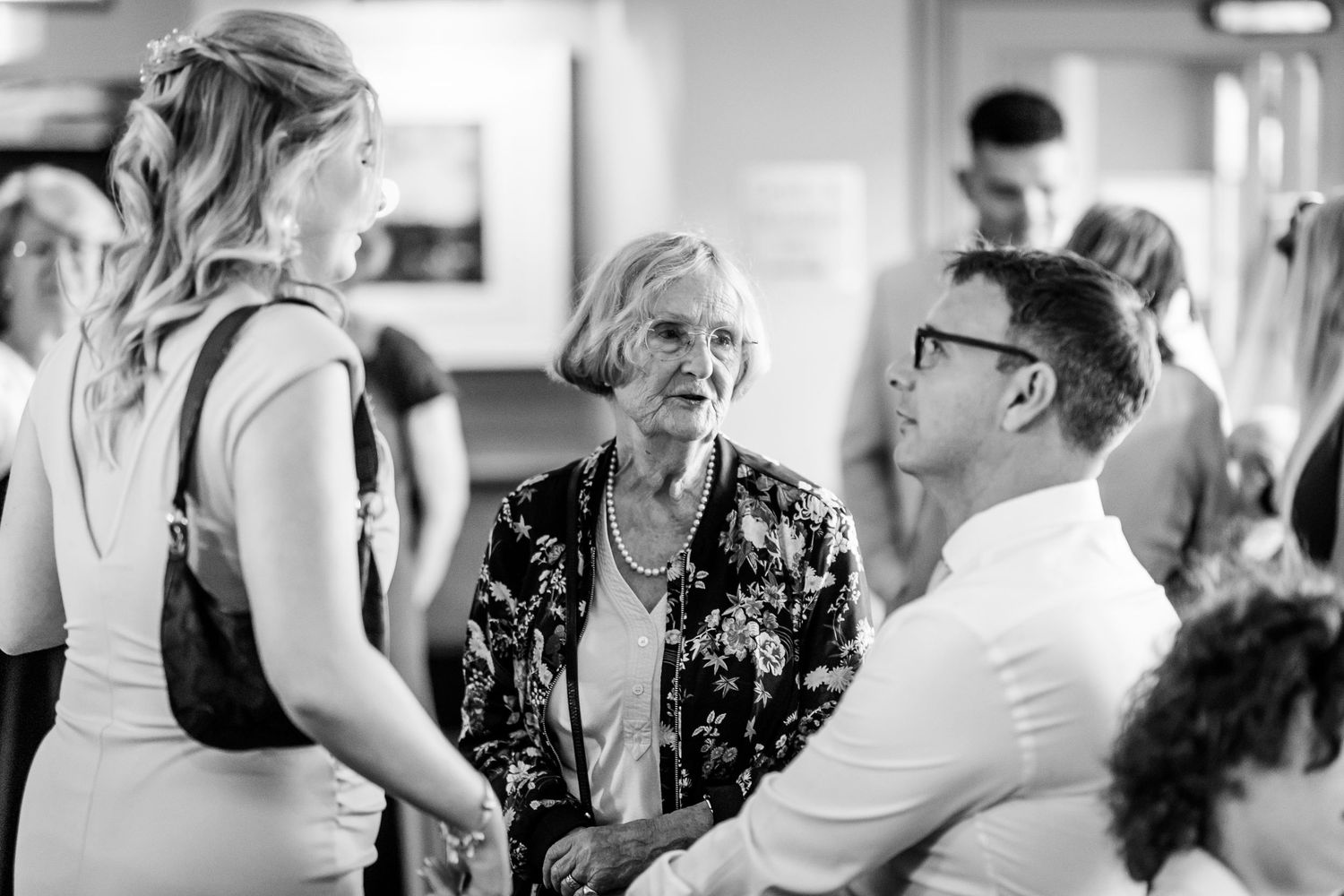 Black and white photo of people socializing at a formal gathering.