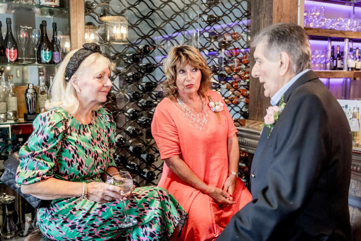 Wedding guests socializing in reception venue with decorative lighting and festive atmosphere.