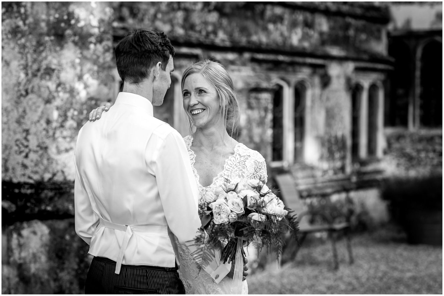 Wedding couple walking together outside historic stone building with elegant architectural details.