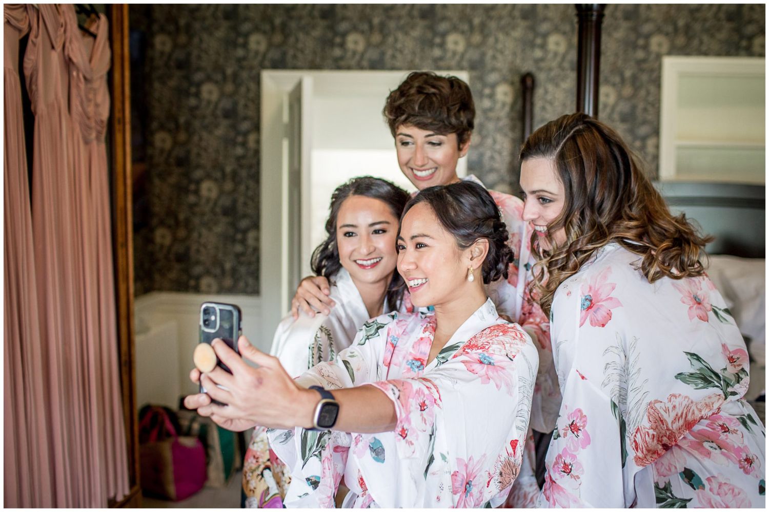 Bridesmaids in floral robes prepare for wedding day celebrations.