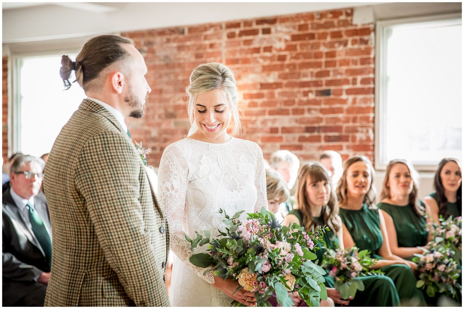 Wedding venue decorated with greenery against exposed brick walls and natural lighting.