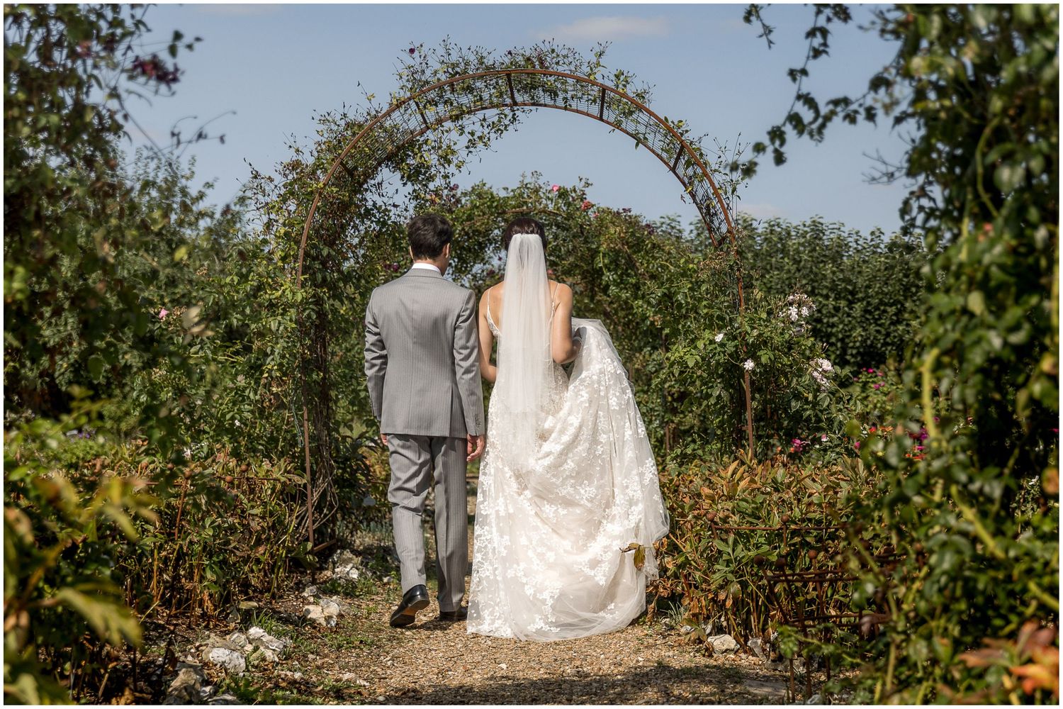 Outdoor wedding ceremony setup with floral arch and garden backdrop.