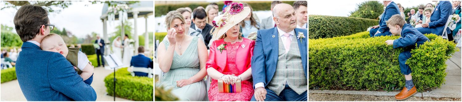 Wedding party members in blue and pink attire gather outdoors near a classic white gazebo.