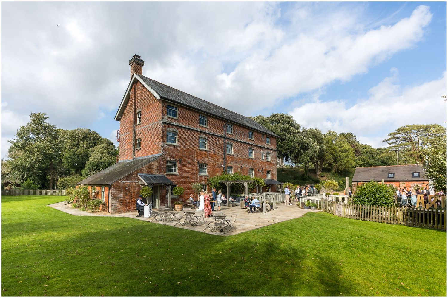 Panoramic view of a rustic brick venue with manicured gardens and blue sky.