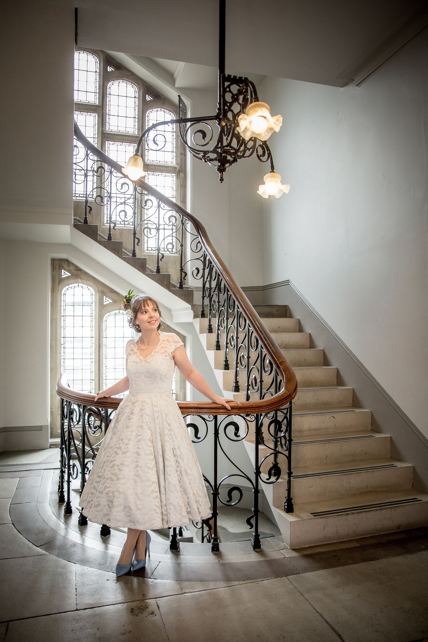 Elegant vintage staircase with ornate iron railings and arched windows in wedding venue.