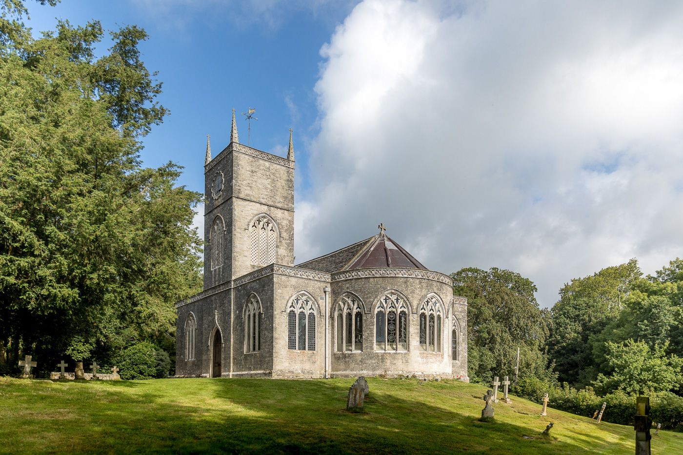 Panoramic view of a classic stone church and grounds under blue summer skies.