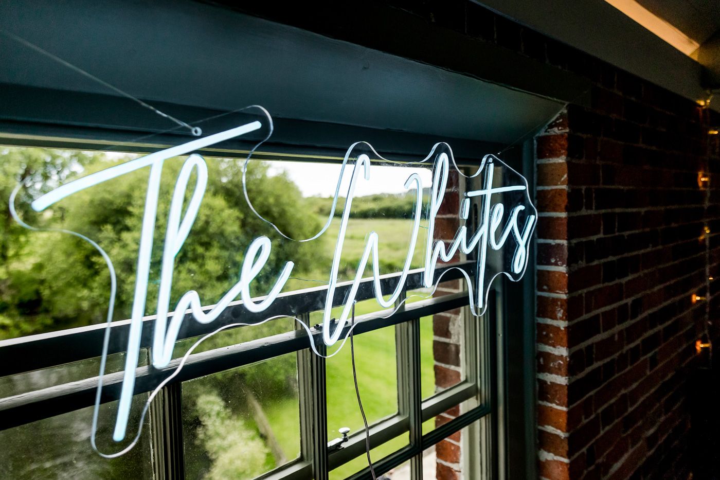 Glowing neon 'The Lights' sign mounted on a window with green foliage visible outside.
