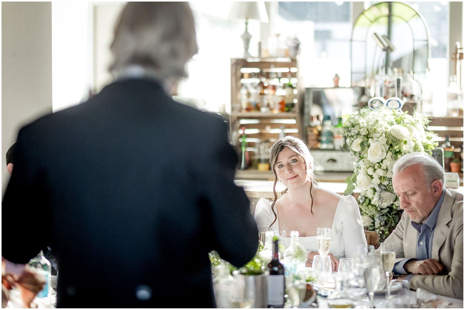 Bright reception hall with large windows and elegant table settings for wedding guests.