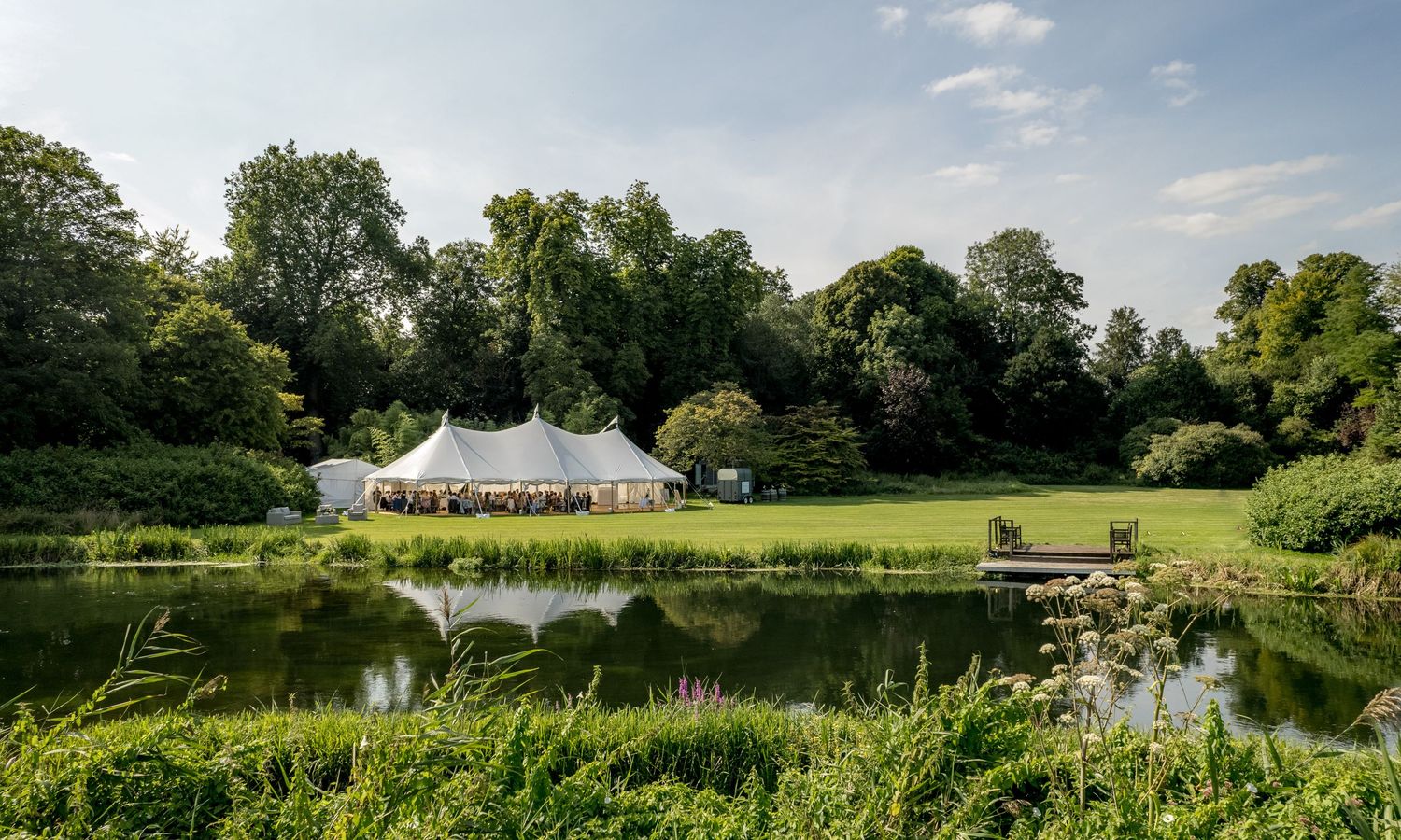 Scenic views of the River Test surrounded by lush greenery with the wedding reception marquee and Houghton lodge in the distance.