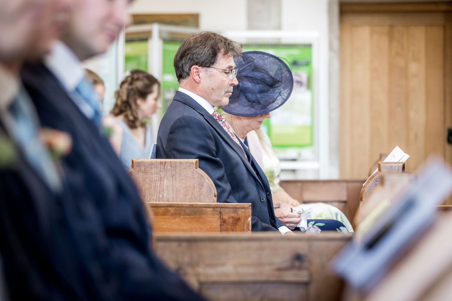 Wedding ceremony guests seated in wooden church pews during service.