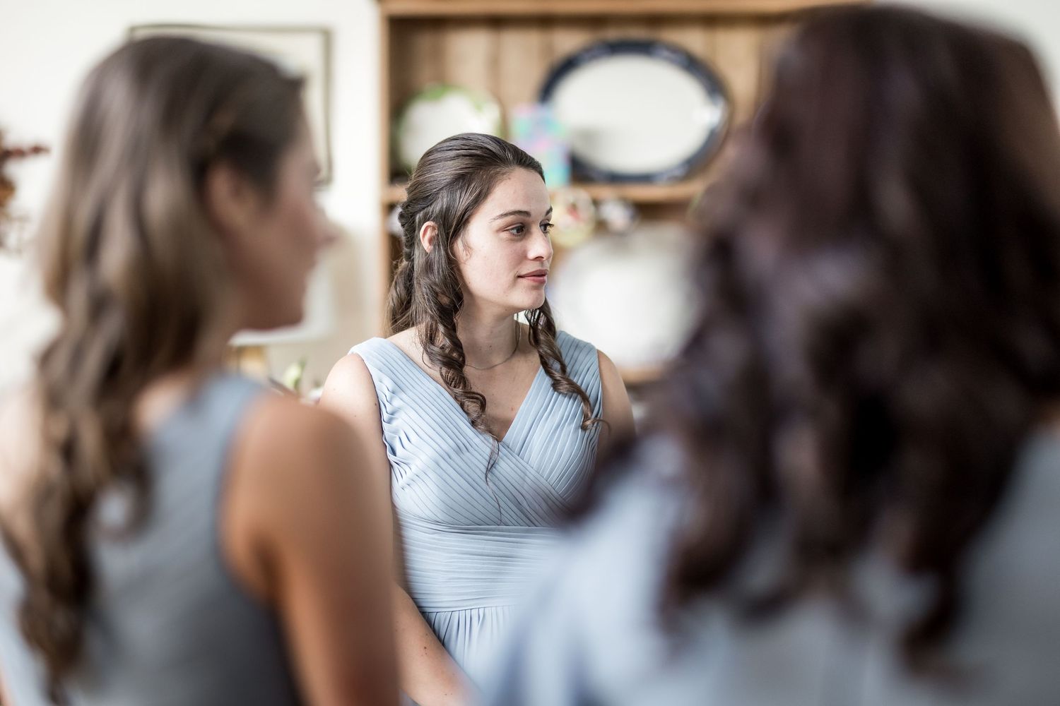 Wedding preparation scene with bridesmaids in powder blue dresses gathered in a bright room.
