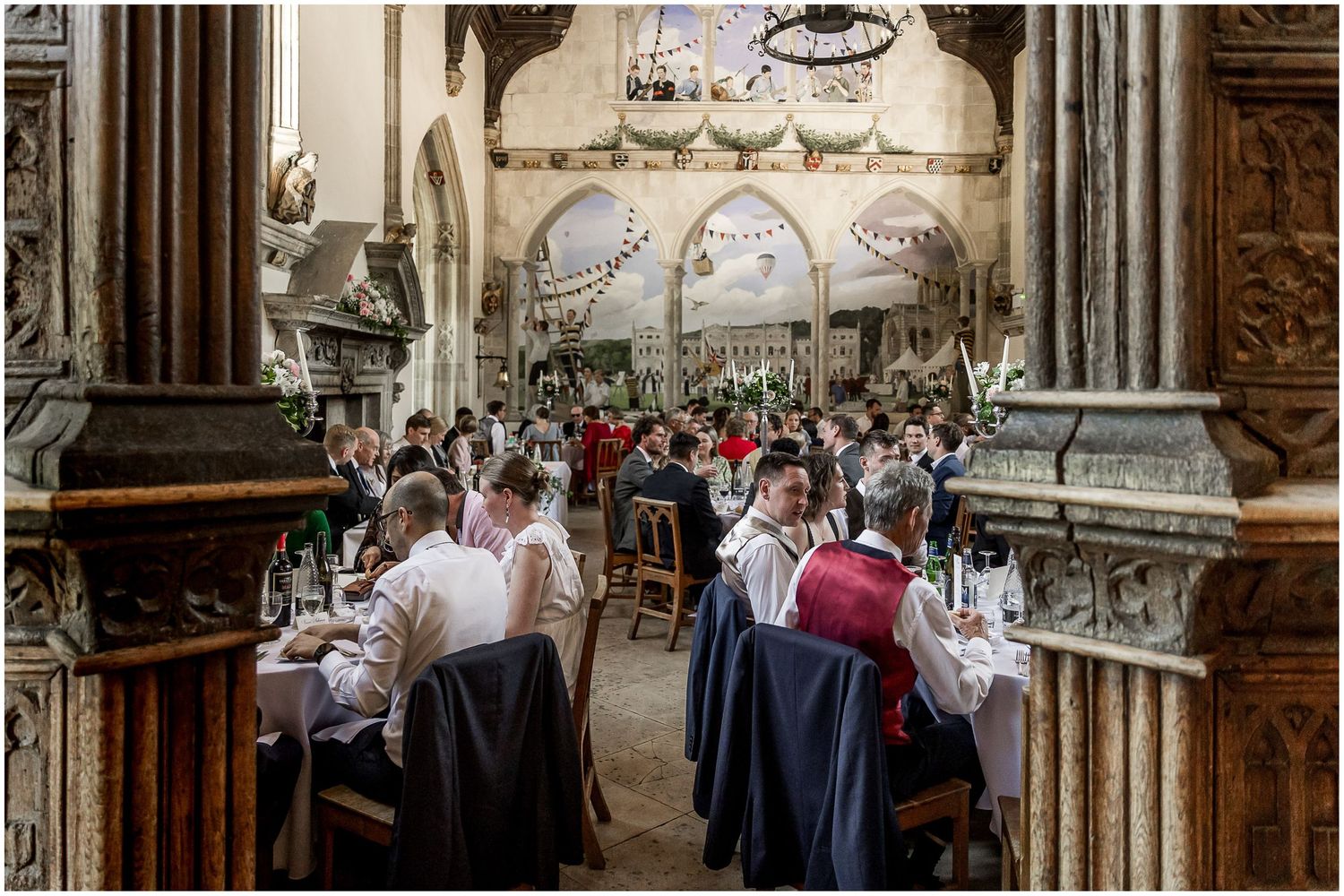 Guests dining in an ornate gothic-style hall with carved stone pillars and arched ceilings.