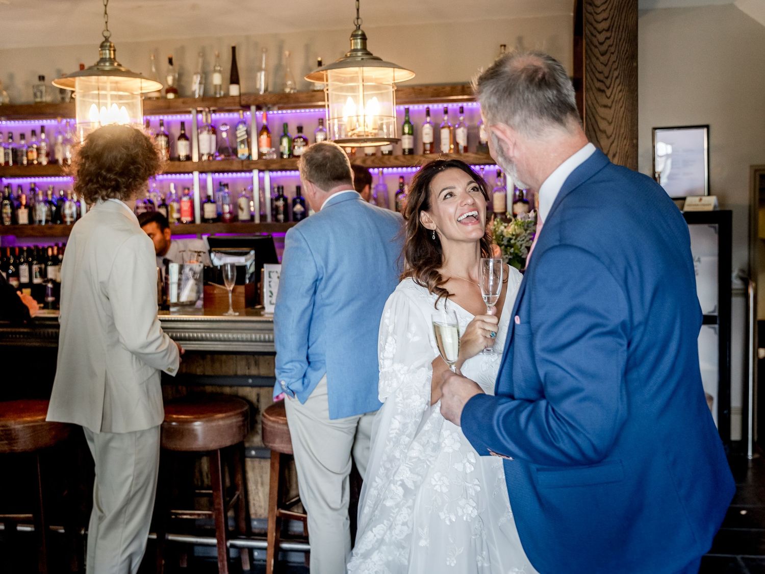 Reception venue with bar area illuminated by purple lighting and hanging pendant lamps.