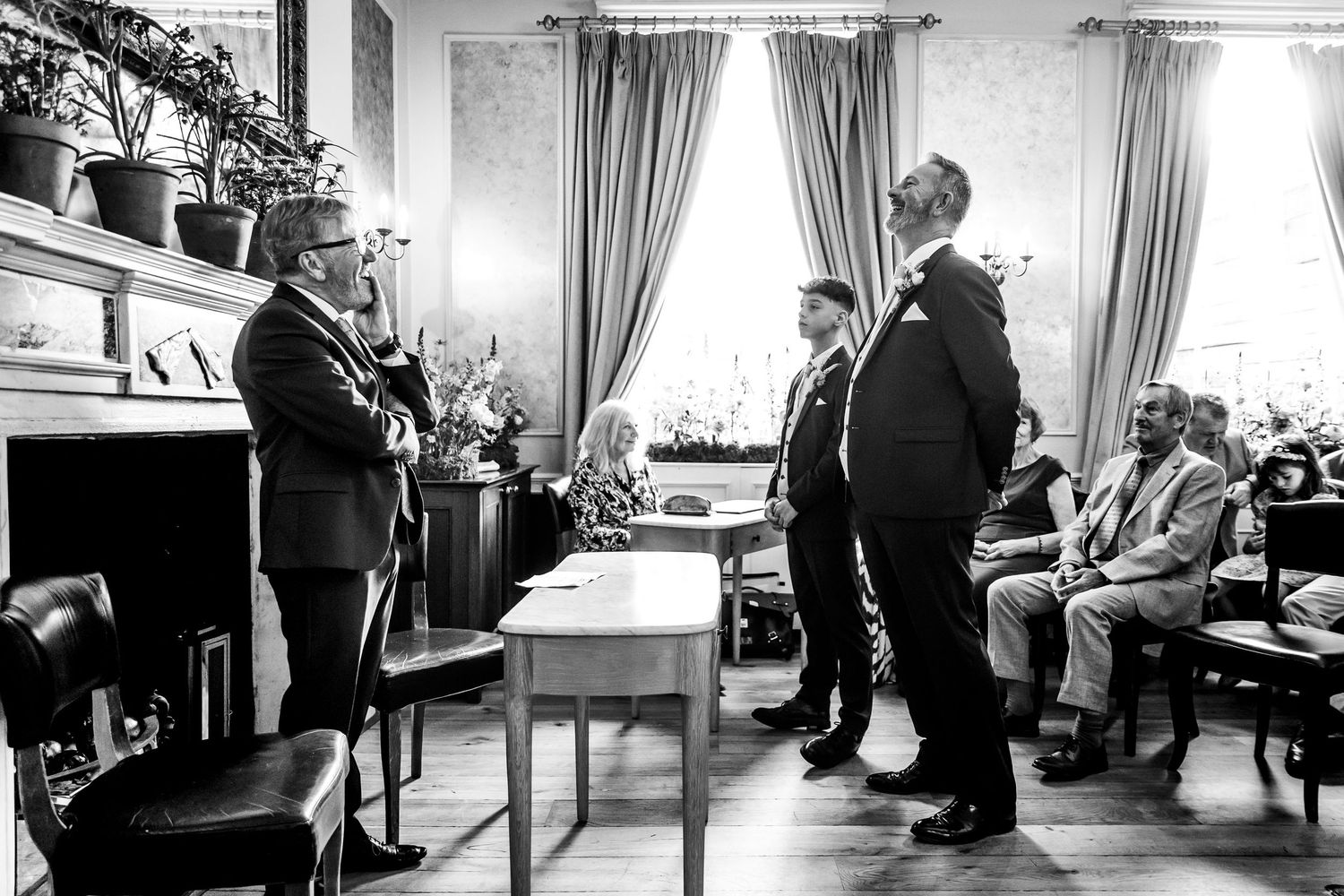 Black and white panoramic view of wedding reception with guests seated at tables.
