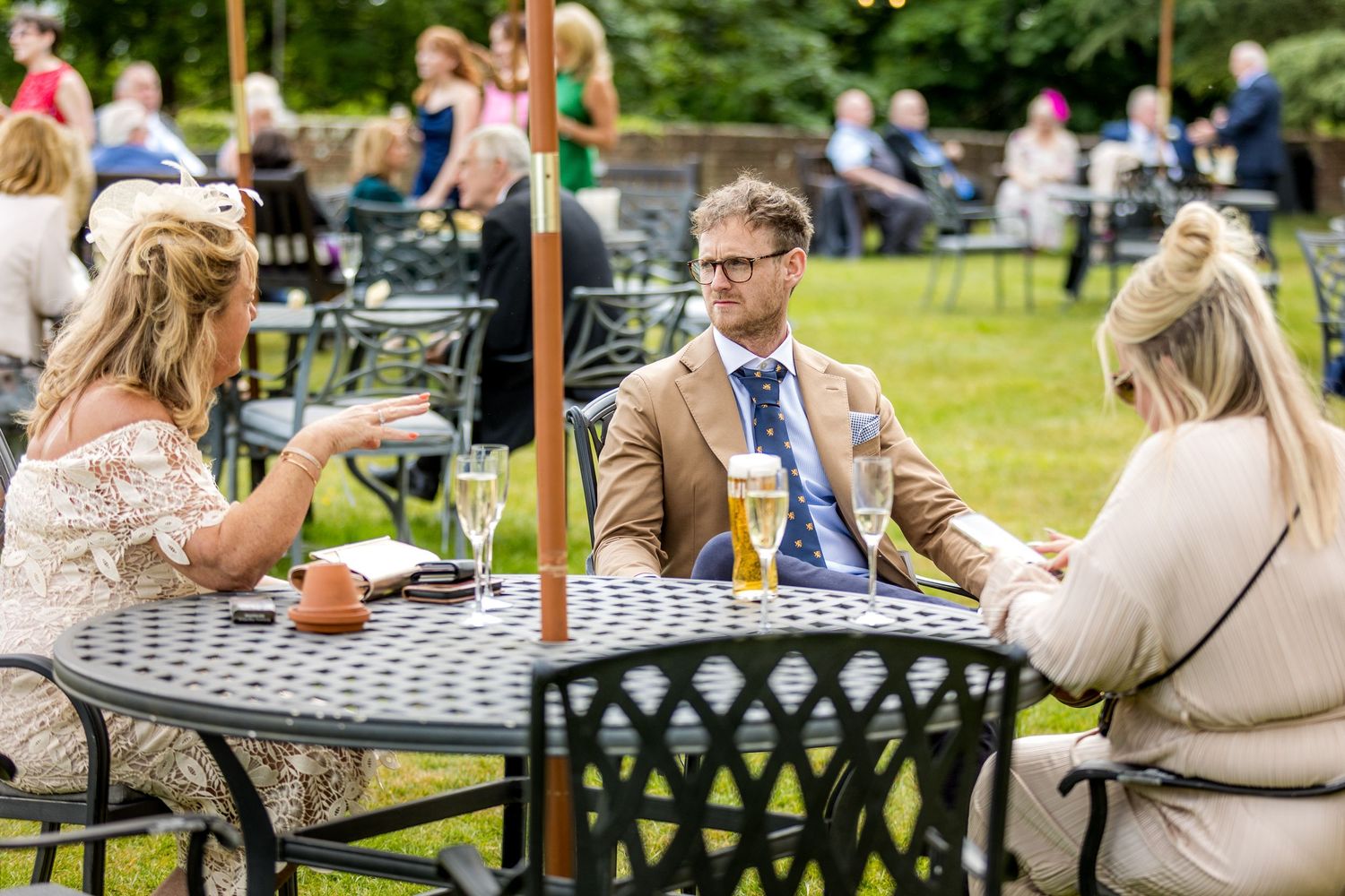 Wedding guests enjoying refreshments at outdoor tables on castle grounds.