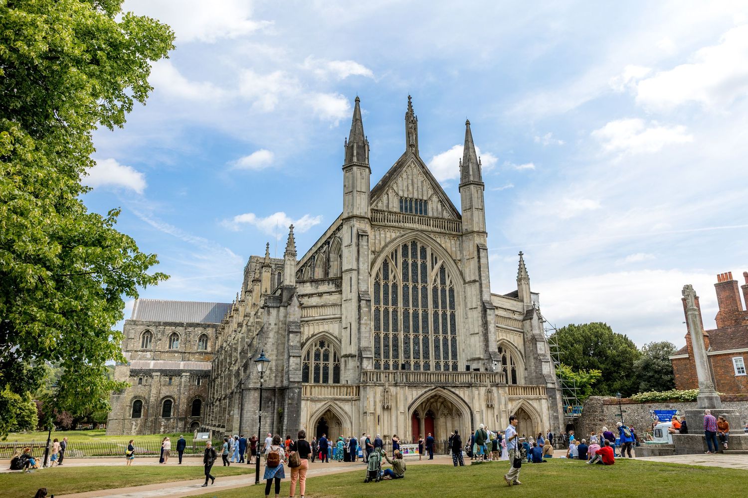 Panoramic view of Winchester Cathedral exterior with gothic spires against blue summer sky.