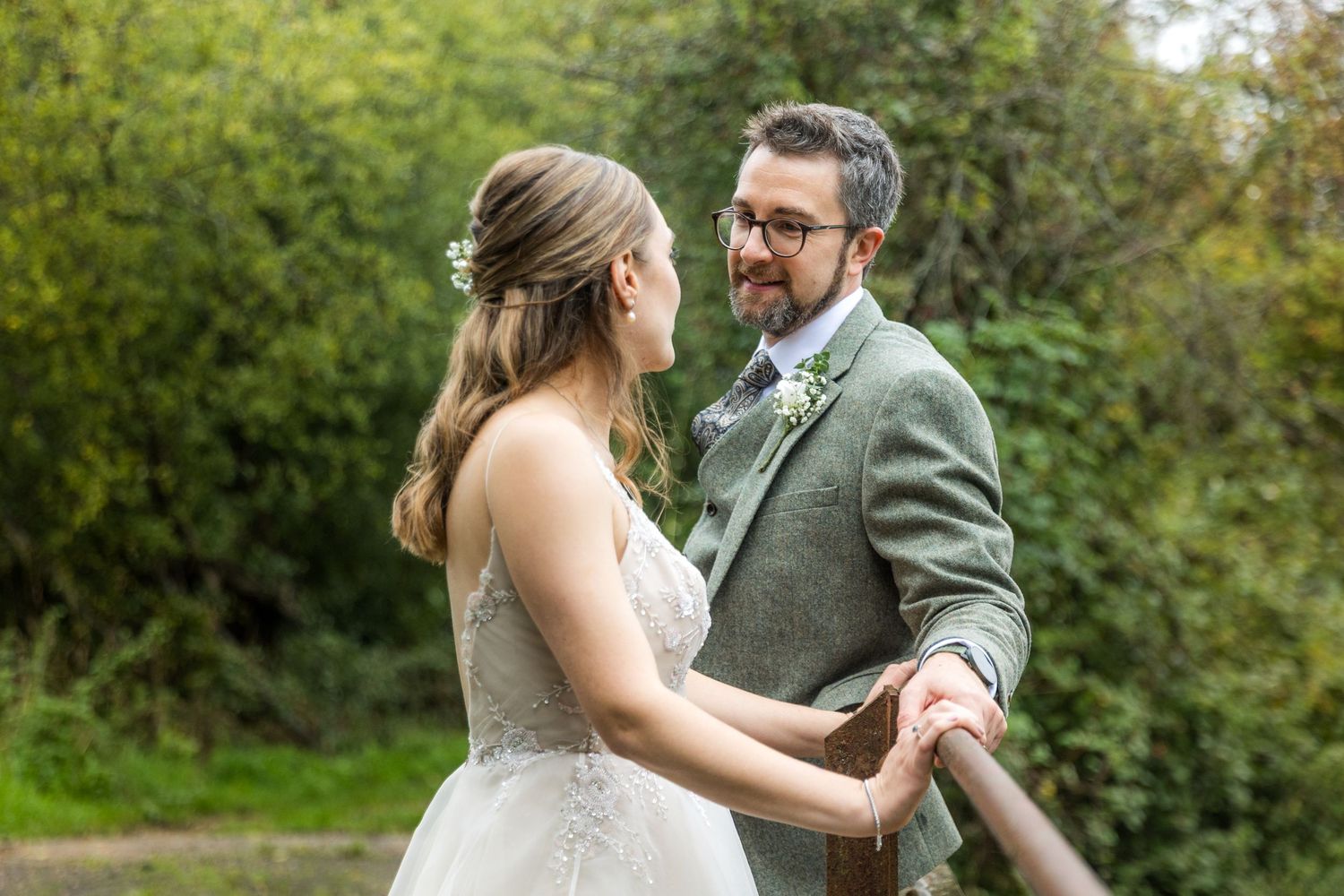 A couple in wedding attire share intimate moments in a lush garden setting during their wedding photoshoot.