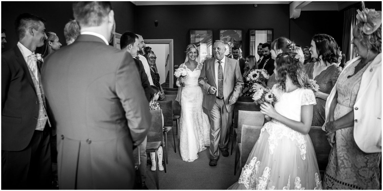Wedding guests dance and celebrate together on a dimly lit dance floor during an evening reception celebration.