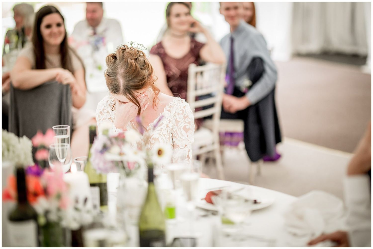 Wedding guests enjoying a celebratory reception dinner with wine glasses and floral centerpieces on elegant tables.
