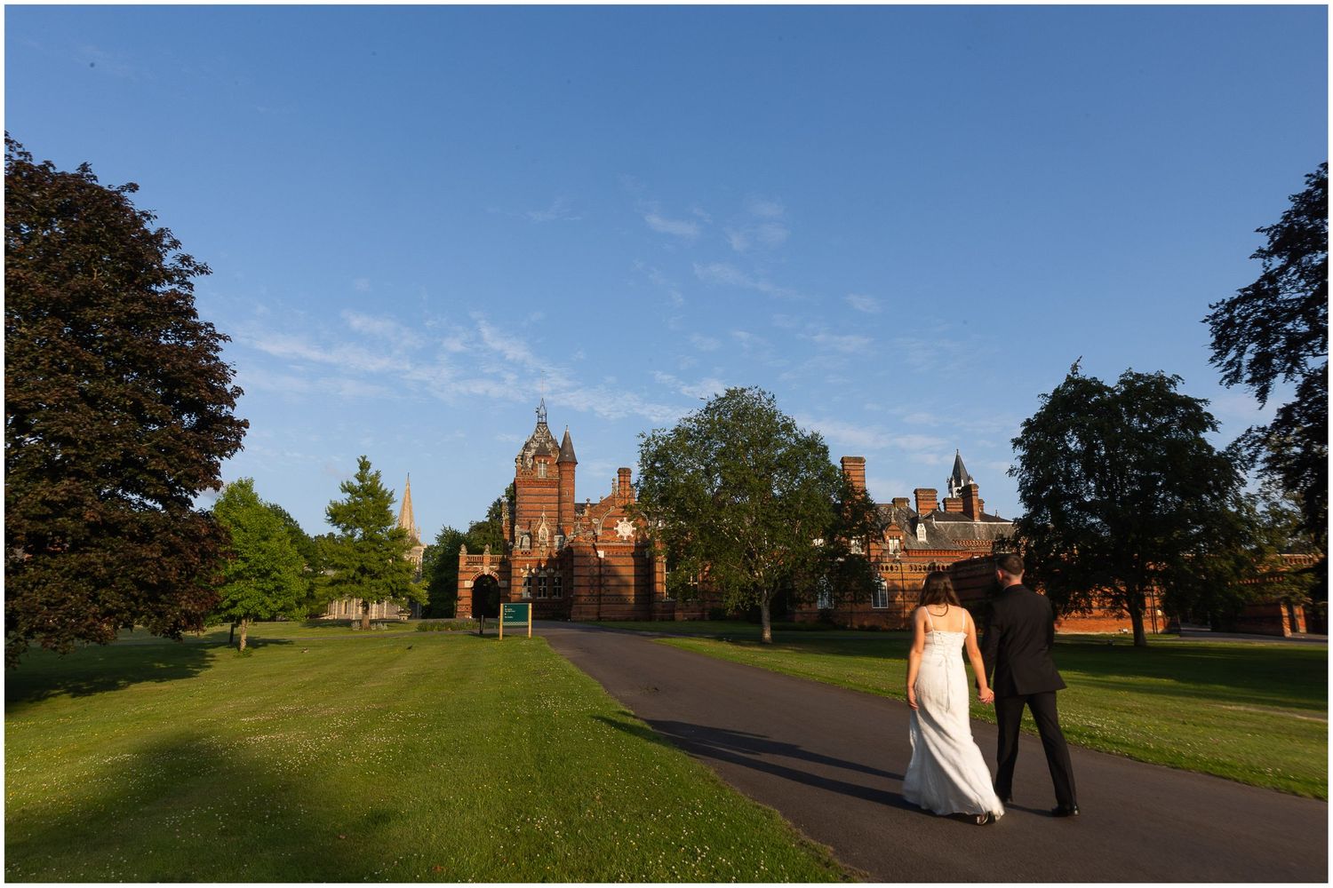 The bride and groom walk in the evening light towards the Elvetham hotel wedding venue in Hampshire