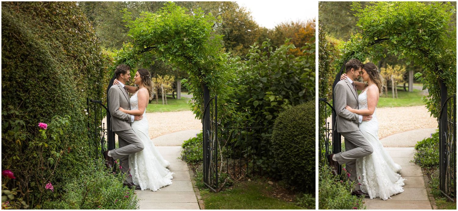 Wedding photograph with bride and groom framed by a floral arch outside the Farmhouse at Clock Barn near Winchester