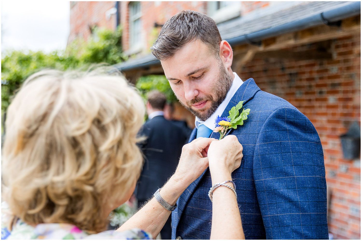 The groom's mother pins a button-hole to his lapel as a finishing touch before the ceremony.