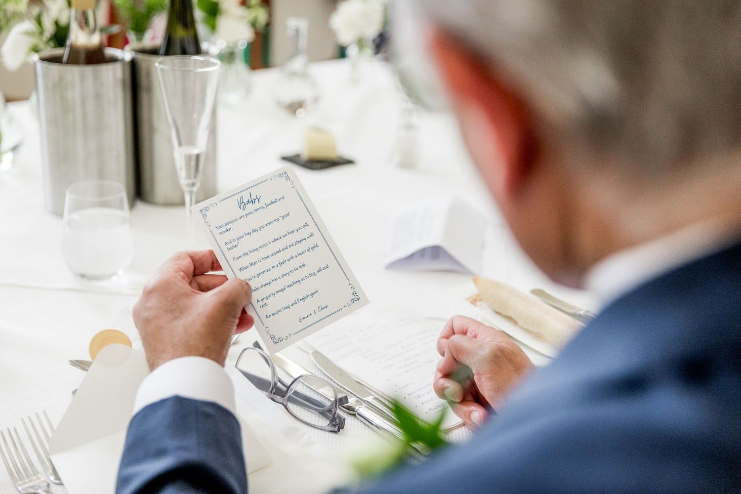 Close-up of wedding reception table settings with white linens and printed menus.