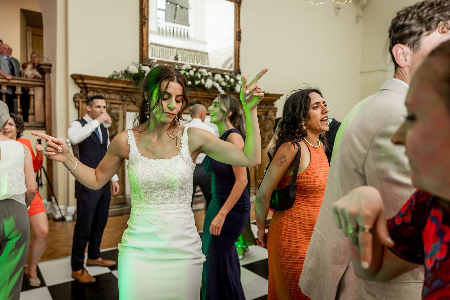 Wedding celebration in full swing with guests dancing in formal attire and colorful dresses.